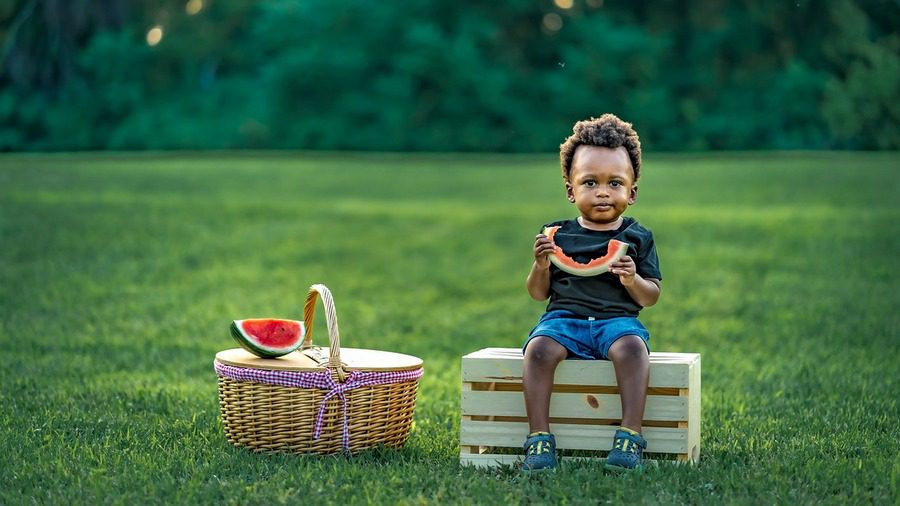 Bambino che mangia il cocomero in campagna